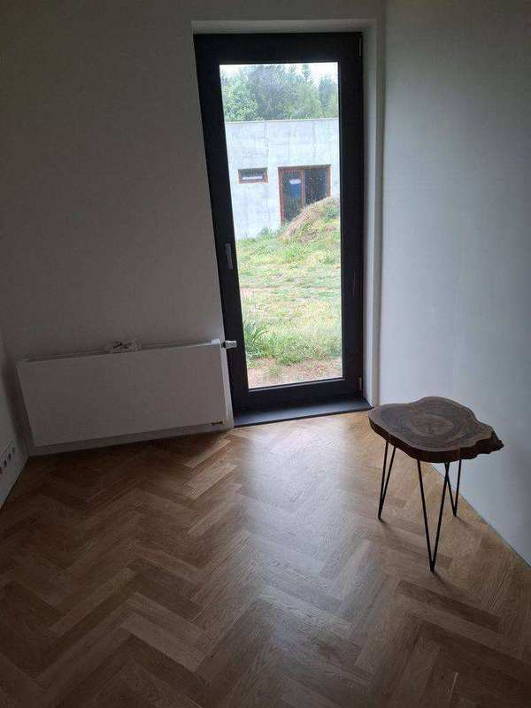 Dokončený pokoj s dubovým rybinovým parketem, radiátorem a francouzským oknem do zahrady