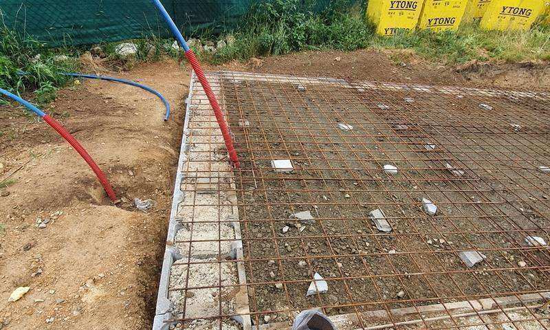 Chráničky pro elektroinstalaci a kanalizační PVC trubky vyvedené z výkopu před betonáží základové desky