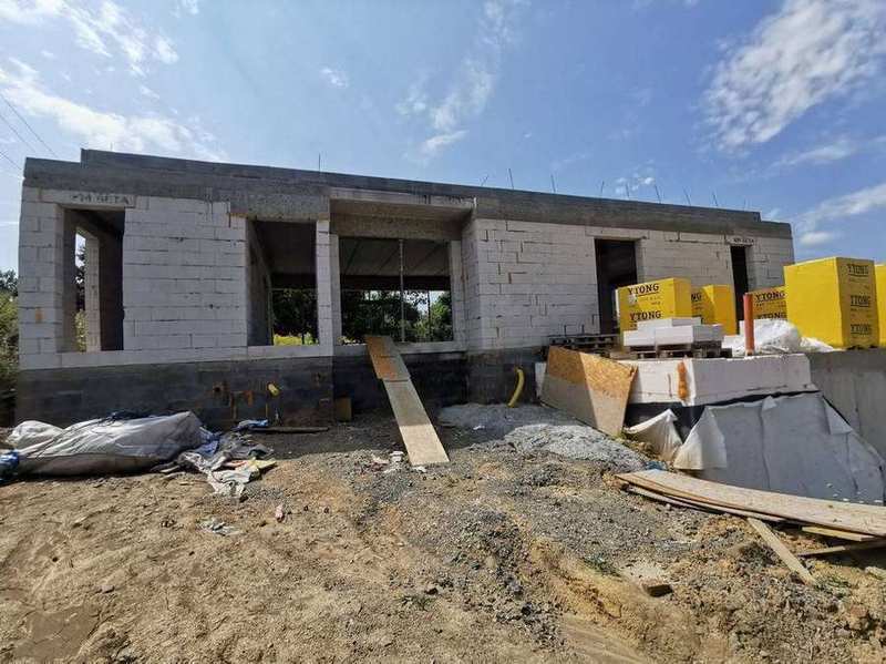 Přední pohled na hotovou korobku dvoupodlažního rodinného domu z Ytongu a KM Beta bloků – ŽB věnce a palety materiálu