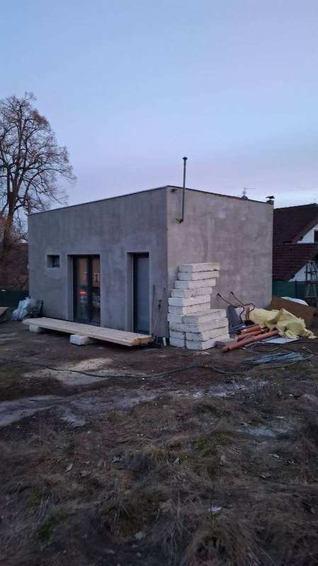 Rohový sprchový kout sauny s hydroizolační stěrkou na plátcích keramiky – smrkové palubky na stěnách, krytá kamna zakrytá folií a odtoková vpusť v podlaze