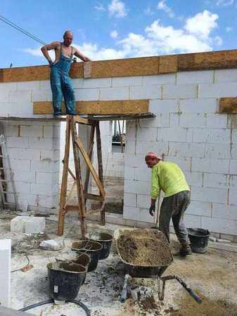 Betonáž železobetonového věnce – pracovníci ukládají čerstvý beton do připraveného bednění